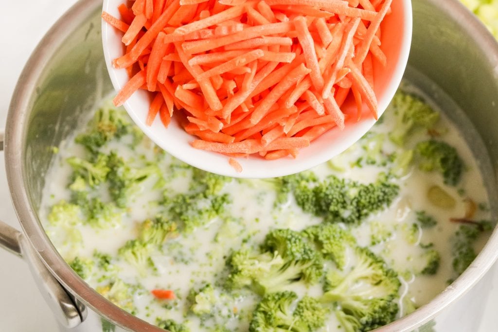 carrots in measuring cup with broccoli in pot