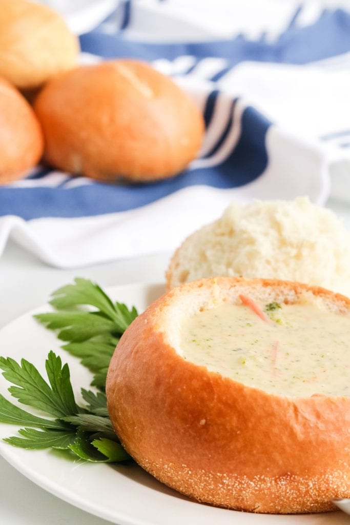 Copycat Panera Broccoli Cheddar Soup in bread bowl with blue linen in background.