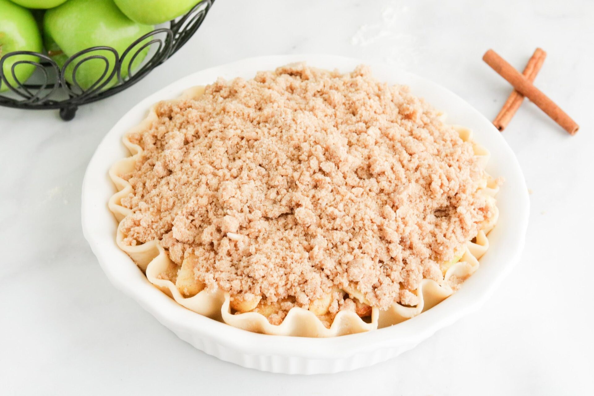 uncooked Apple crumble pie ith white surface