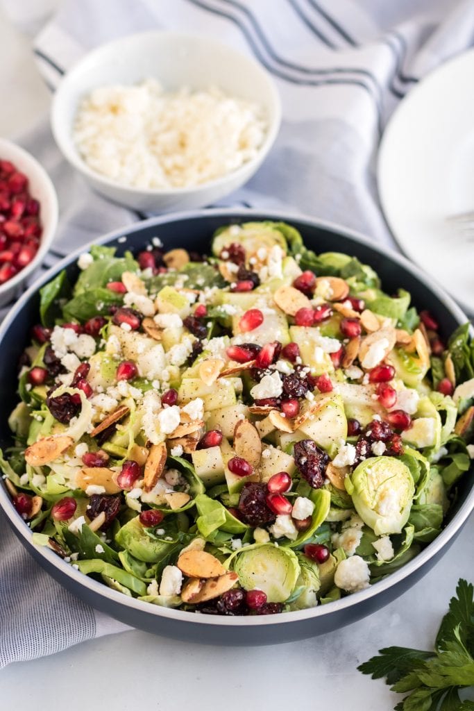 This shaved brussel sprout salad with cranberries, apples, and pomegranates is delightfully refreshing and tastes delicious! Wow your guests with this simple brussel sprout salad recipe with homemade honey mustard dressing.