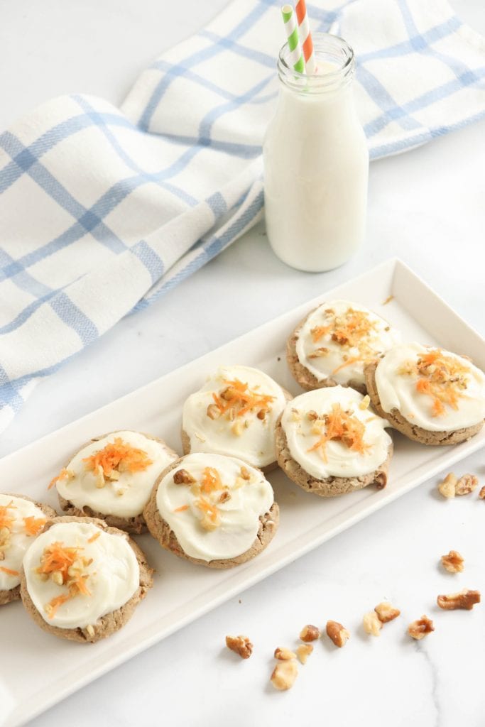 carrot cake mix cookies on white platter serving plate with shaved carrots and chopped walnuts