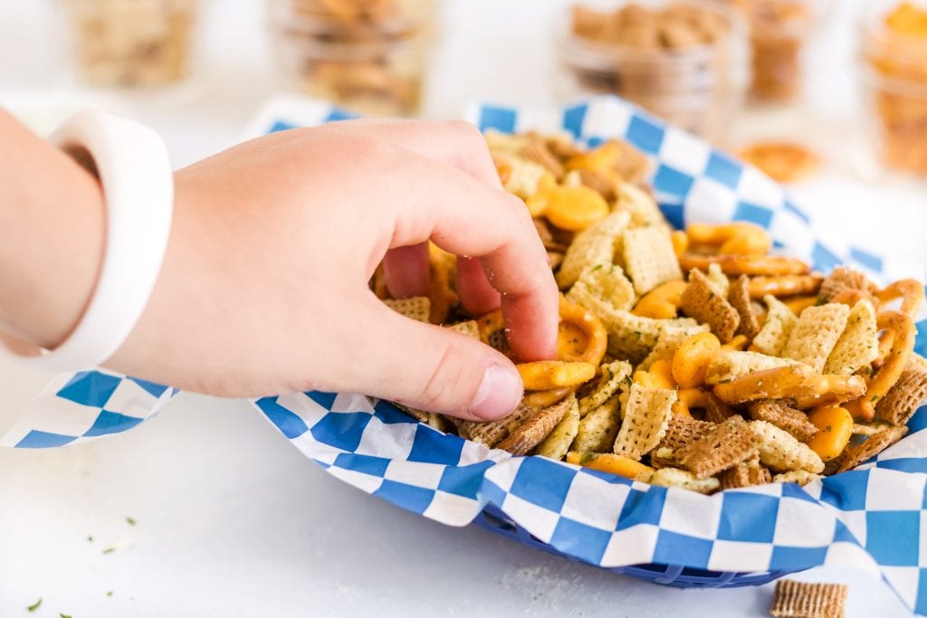 close up of hand grabbing air fryer Chex mix