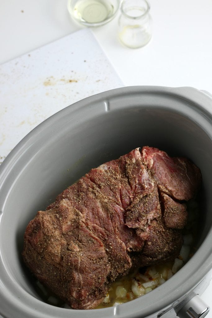 uncooked pork roast sitting in a slow cooker