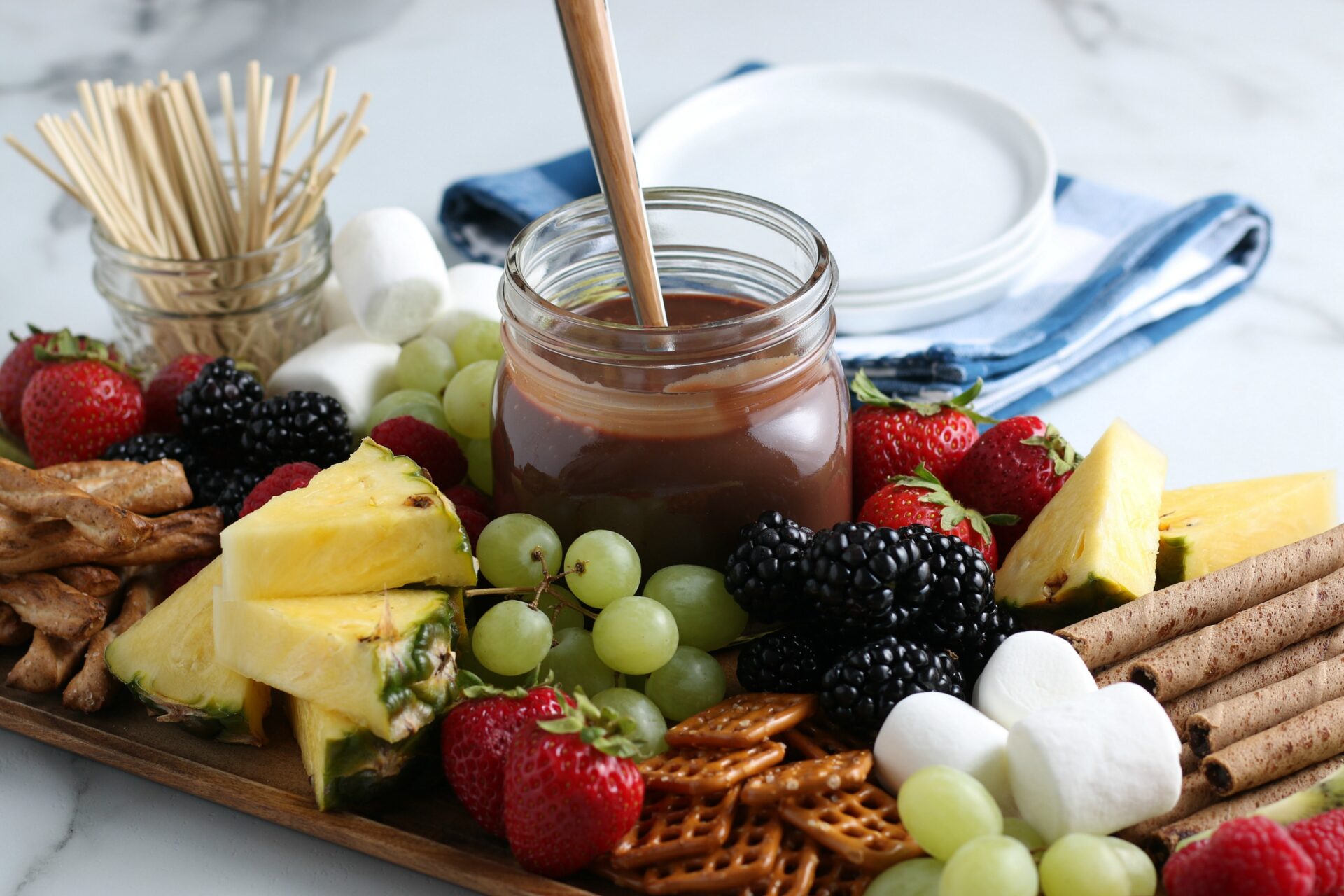 chocolate sauce and assorted dipping items on a wooden tray