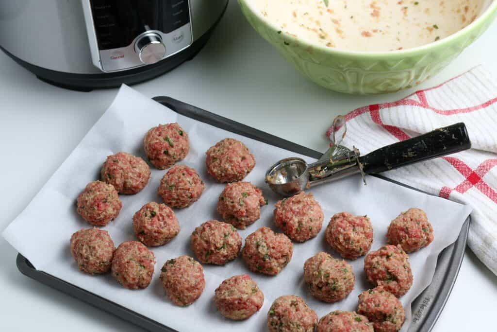 The meat mixture is shaped into 1-inch balls on a baking sheet with parchment paper. 