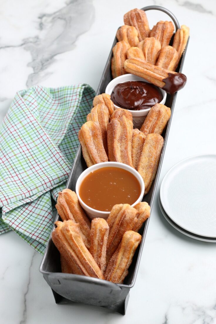 air fryer churros dipped in cinnamon sugar with caramel and chocolate sauces