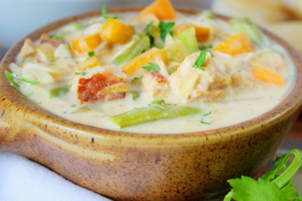 close up of chicken pot pie soup in a speckled brown bowl