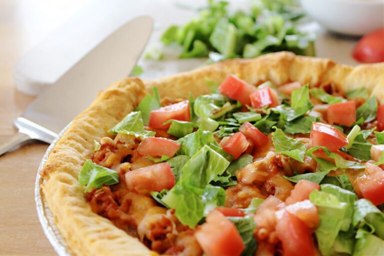 taco bake with lettuce and tomato by a serving utensil
