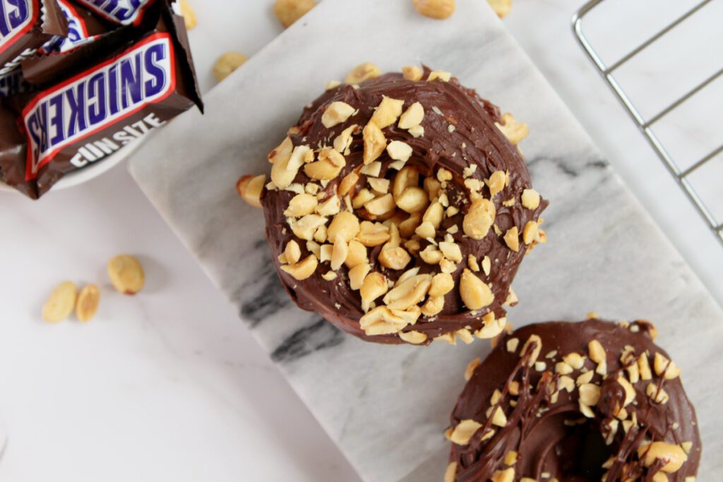 overhead shot of snickers donut on a marble tray