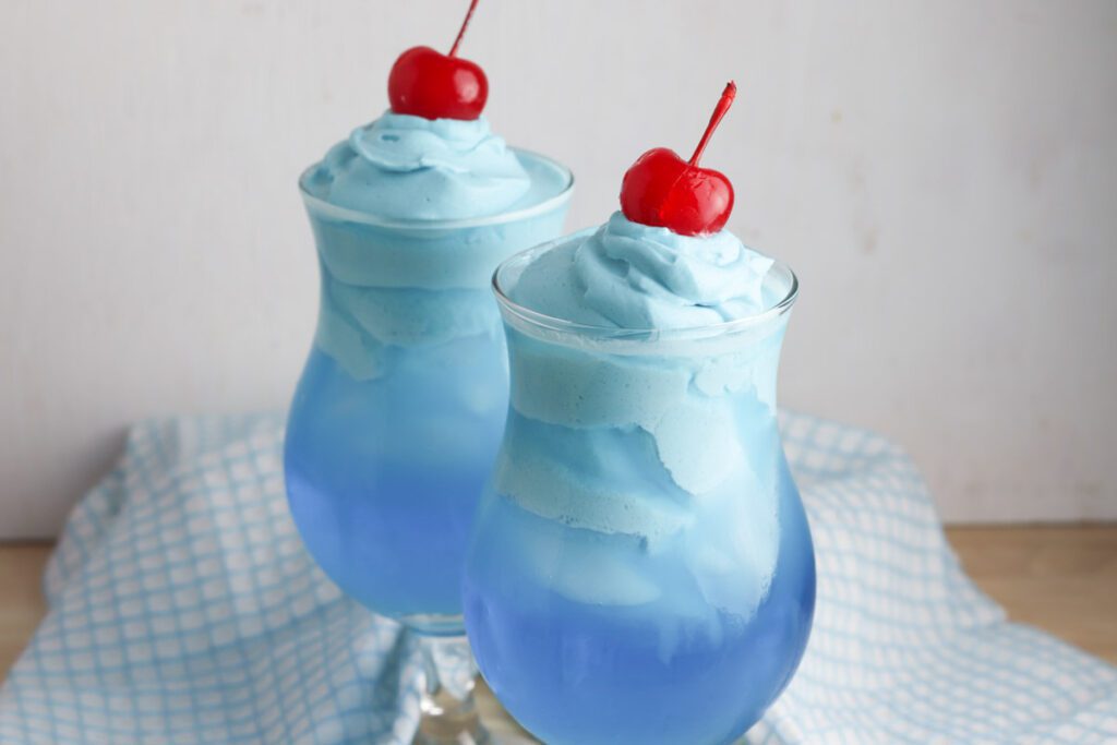 2 glasses of whipped kool aid recipe sitting by a blue gingham tea towel