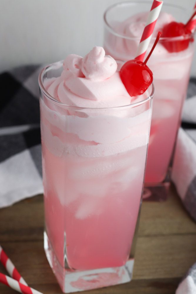2 glasses of pink whipped lemonade with red striped straws