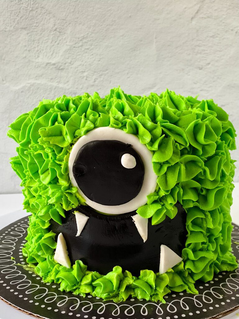 monster cake with diy fondant decorations on a brown and white cake board