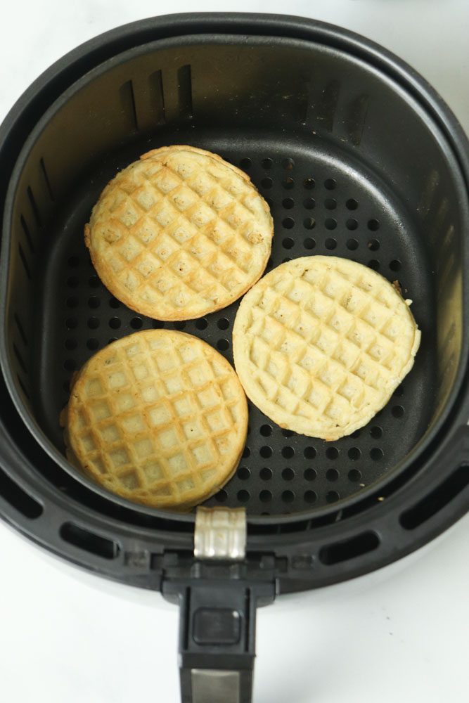 frozen waffles sitting in an air fryer basket cooked