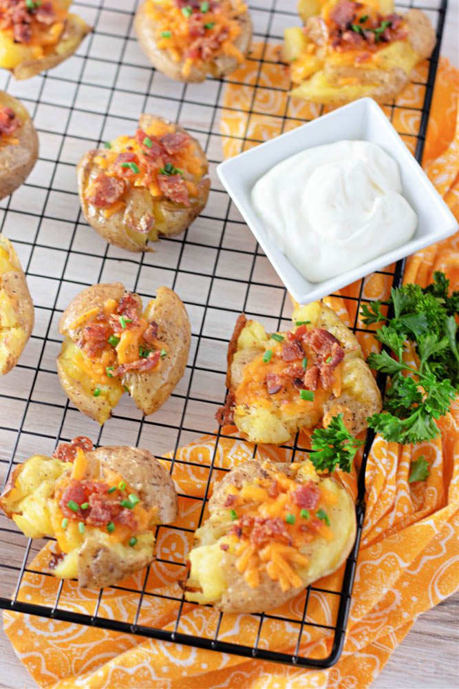 loaded smashed potatoes with on a cooling rack with garnishes