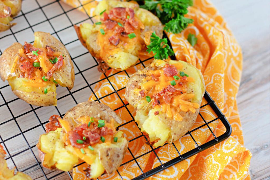 loaded smashed potatoes on a wire rack with orange cloth