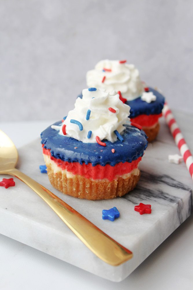 Patriotic Mini Cheesecakes on marble with whipped cream and sprinkles