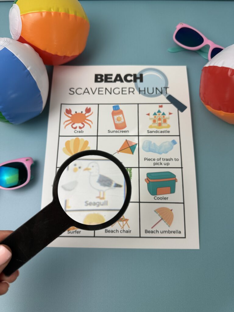 closeup of beach scavenger hunt pdf on but background looking through magnifine glass