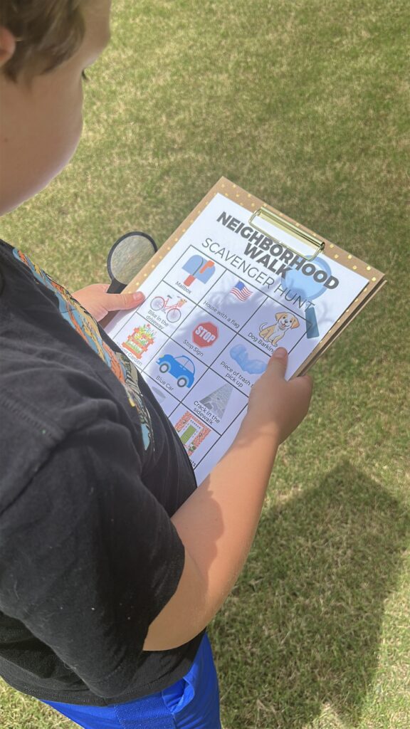 boy holding clipboard outside with neighborhood scavenger hunt