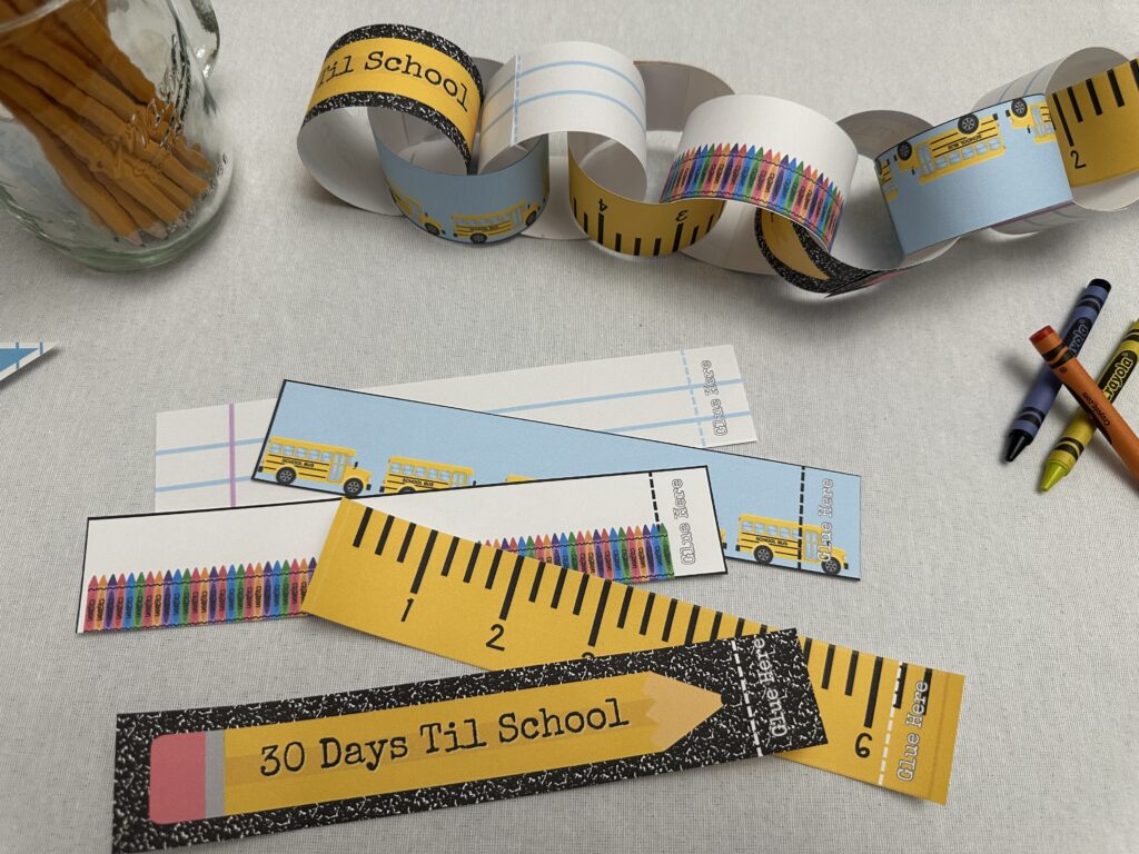 View of a back-to-school paper countdown chain and printable strips laid out on the table, ready to be assembled with scissors and crayons nearby.