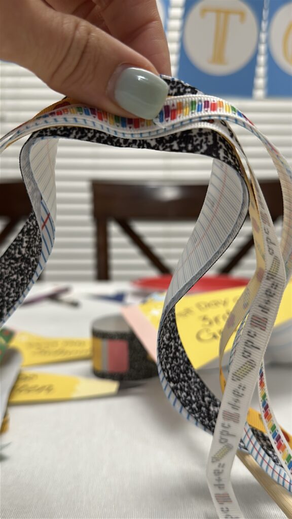 Close-up of colorful school-themed ribbons (lined paper, notebook print, ruler design) used for flag decorations.