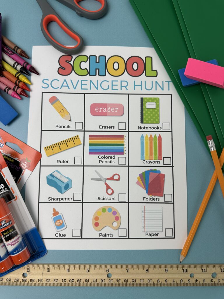Flat lay of the completed school scavenger hunt printable with real supplies including glue, rulers, pencils, folders, and crayons placed neatly around the page.