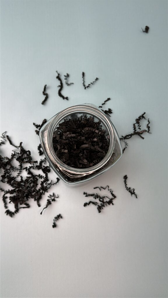 jar filled with black paper shred, perfect base for a Halloween treat jar craft.