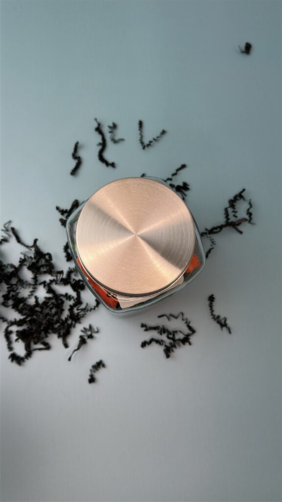 Glass jar with candy sealed with a silver lid, ready for mummy gift tag craft.