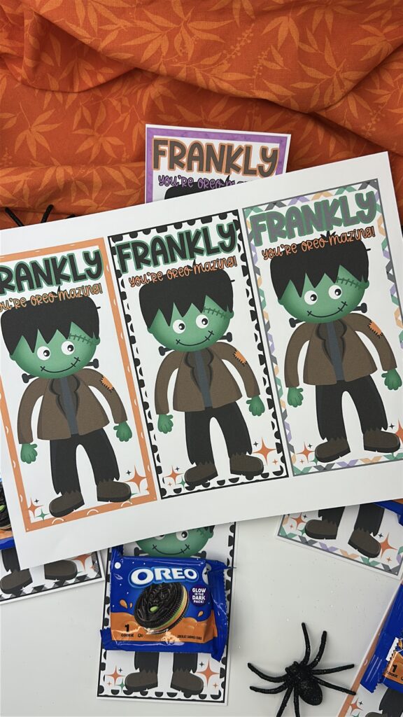 Printed Frankenstein Halloween treat cards on orange fabric with Oreos and spiders scattered around.