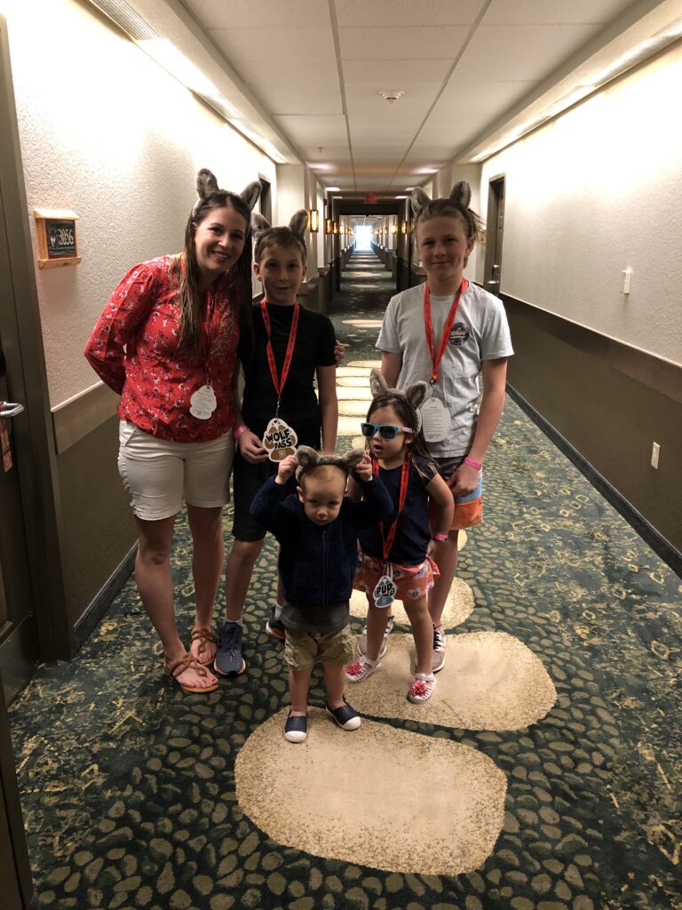 Family walking down the hallway at Great Wolf Lodge with Wolf Pass lanyards and wolf ears during their Great Wolf Lodge family vacation.

