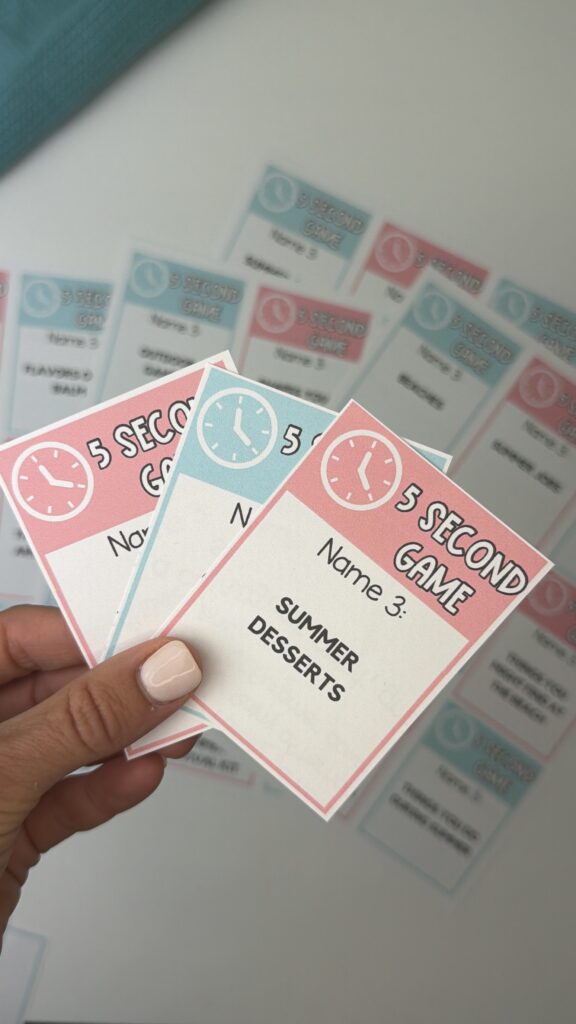 Hand holding summer 5 second game cards with prompts like summer desserts and outdoor games printable activity for kids